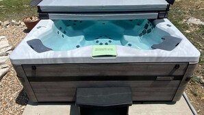 Un jacuzzi con revestimiento de madera, una etiqueta verde y una vista despejada del paisaje circundante.