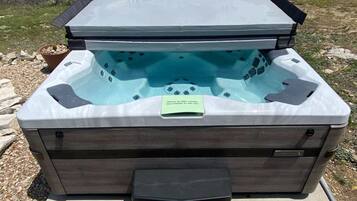 Een hottub met een houten buitenkant, een groen label en een helder uitzicht op het omliggende landschap.