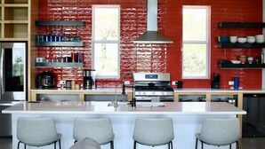 Una cocina moderna con una isla central, electrodomésticos de acero inoxidable y una pared de ladrillo rojo.