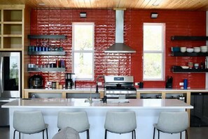 Una cocina moderna con una isla central, electrodomésticos de acero inoxidable y una pared de ladrillo rojo.