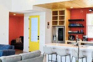 Una cocina moderna con una isla central, un refrigerador y un rebozo rojo.