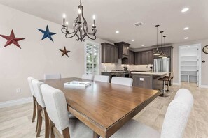 Une cuisine moderne avec des meubles de couleur sombre, un îlot central et des luminaires suspendus.