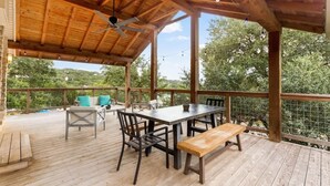 An outdoor wooden deck with a table and chairs, a bench, and a ceiling fan.