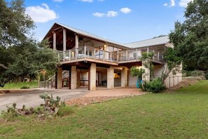 A two-story building with a balcony, a covered patio, and a stone facade.