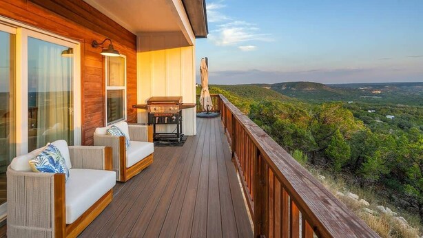 A wooden deck with outdoor seating and a view of the landscape.