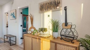 A hallway with a wooden console table, a guitar, and a wall-mounted abstract art piece.