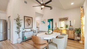 A spacious kitchen with a dining area, a ceiling fan, and a variety of plants.
