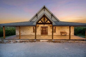 A building with a gabled roof, stone facade, and a wooden bench outside. - Star House | Private Views • Hill Country Comfort (Wimberley)