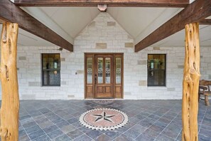 A stone building with a wooden door, two windows, and a star-patterned tile floor. - Star House | Private Views • Hill Country Comfort (Wimberley)