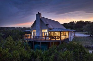 Et moderne hus med stor terrasse, en stenpejs og udsigt til den omkringliggende skov.