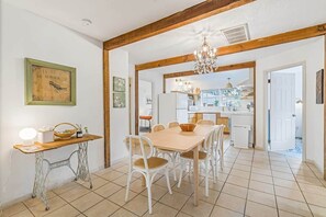 A dining area with a wooden table and chairs, a vintage sewing machine, and a chandelier.