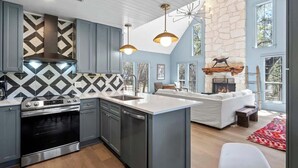 Una cocina moderna con una isla central, horno empotrado y chimenea de piedra.