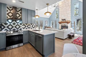 Una cocina moderna con una isla central, horno empotrado y chimenea de piedra.