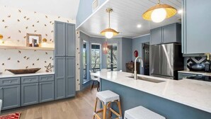 Una cocina moderna con armarios grises, una isla grande y dos taburetes de bar.