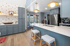Une cuisine moderne avec des meubles gris, un grand îlot central et deux tabourets de bar.