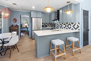 Una cocina moderna con una isla central, taburetes de bar e iluminación colgante.