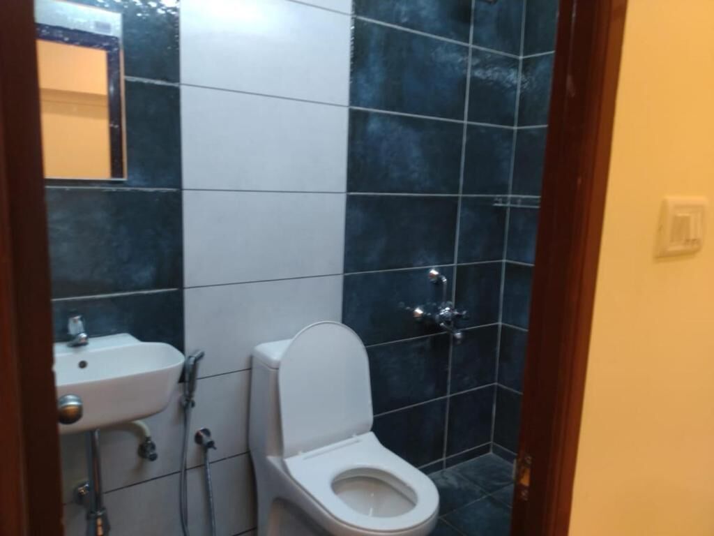 Une salle de bain avec des toilettes blanches, un lavabo et une douche.
