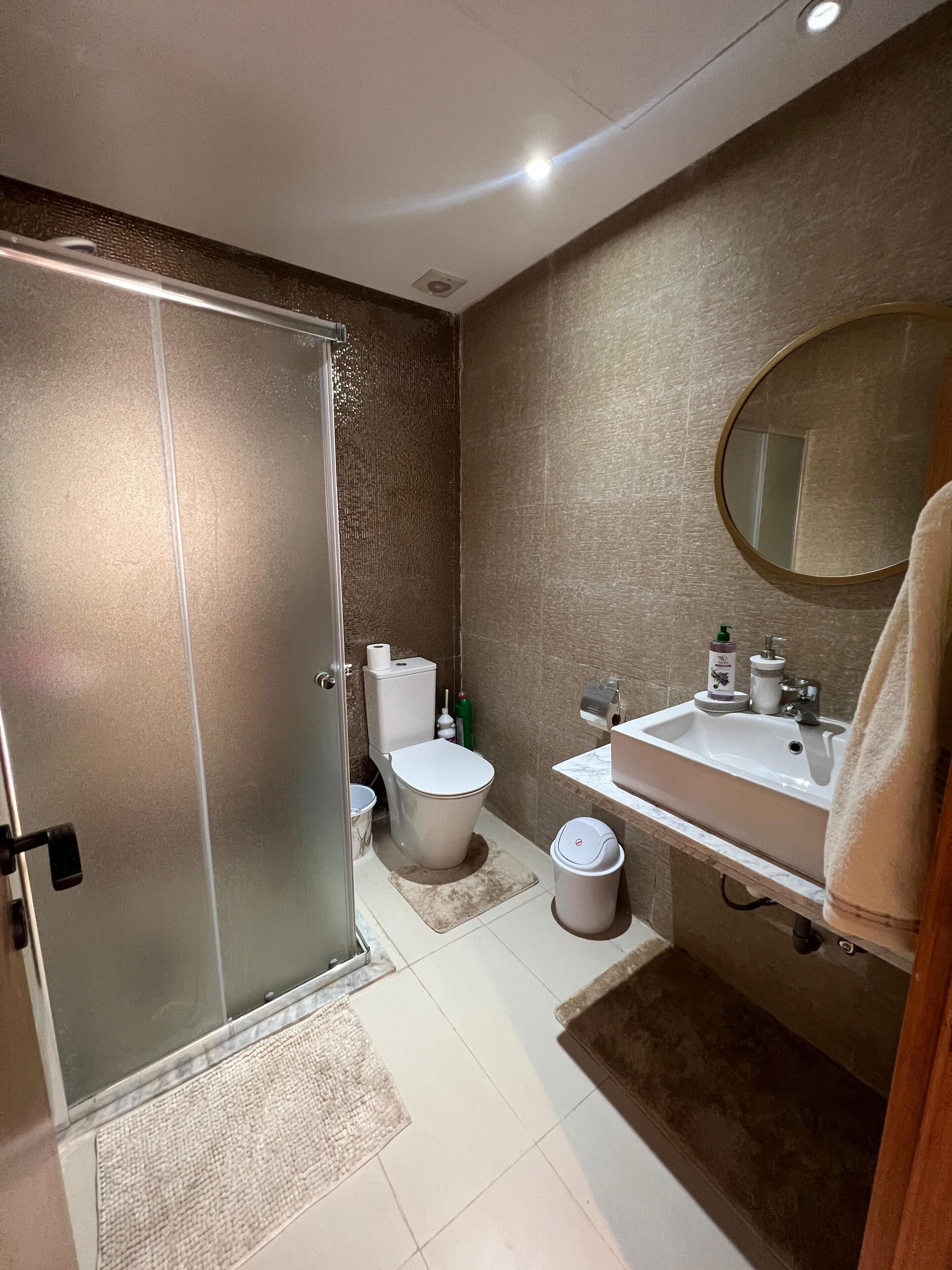 A modern bathroom with a toilet, sink, and shower.