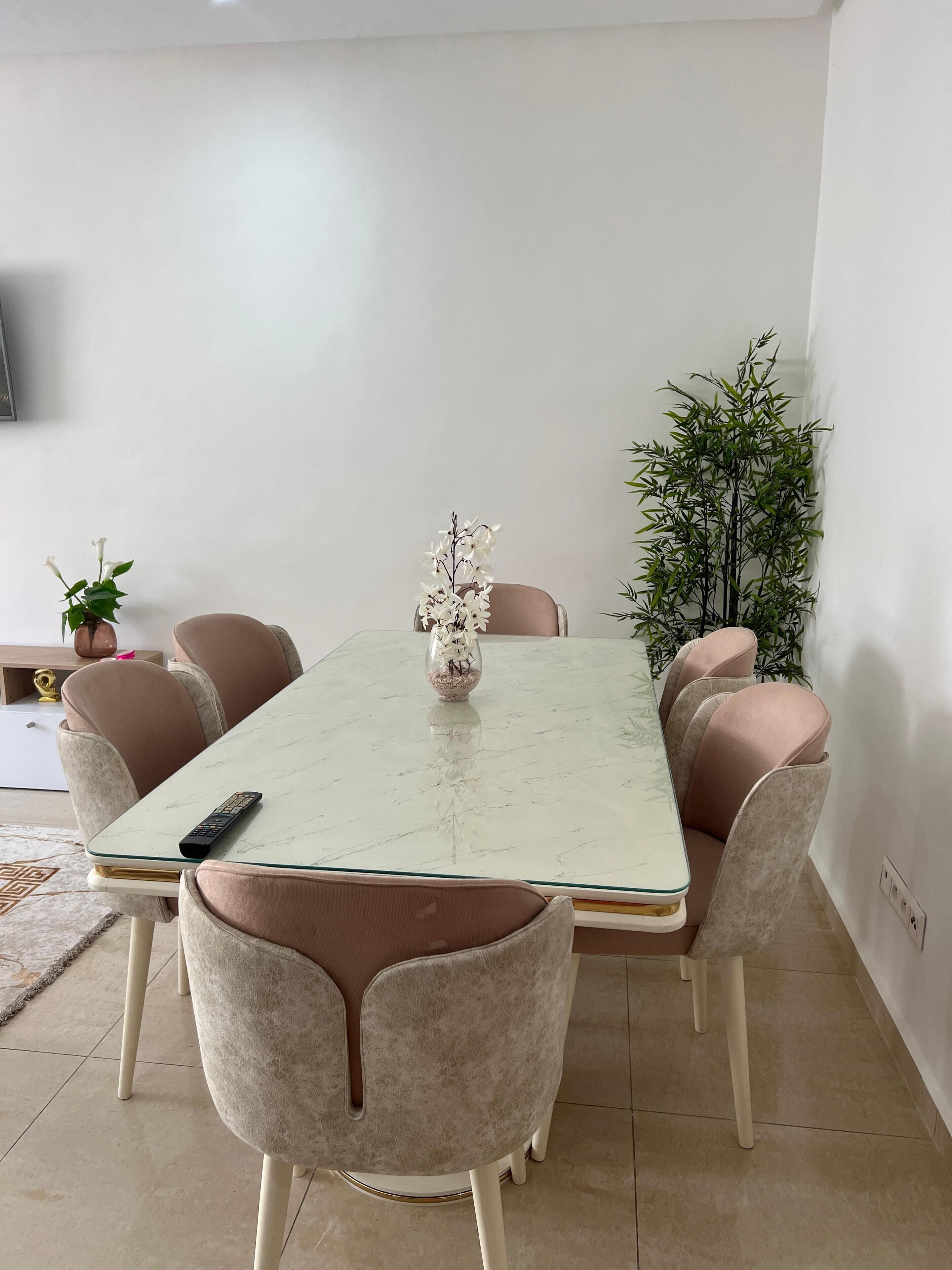 A dining area with a rectangular table, six chairs, and a vase with flowers.