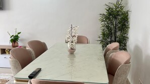 Un coin repas comprenant une table rectangulaire, six chaises et un vase avec des fleurs.