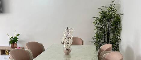 A dining area with a rectangular table, six chairs, and a vase with flowers.