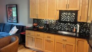 A kitchen with wooden cabinets, a black countertop, and a tiled backsplash. - Delightful 1-bedroom condo in Clemson. (Clemson)