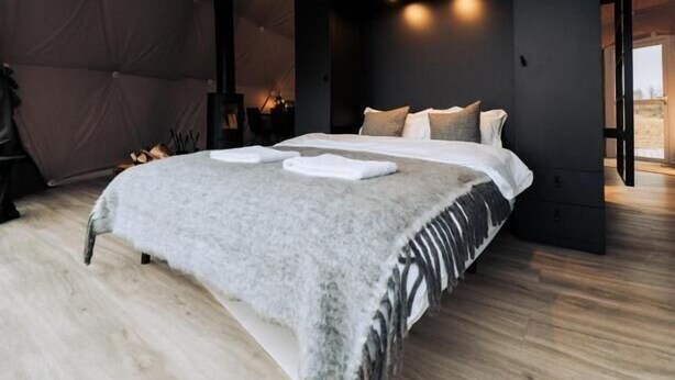 A modern bedroom with a large bed, a geometric ceiling light, and a wooden floor. - Golden Circle Domes - Lake View (Selfoss)