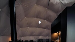 A cozy, modern tent-style living space with a central fireplace, a dining area, and a kitchen area. - Golden Circle Domes - Lake View (Selfoss)