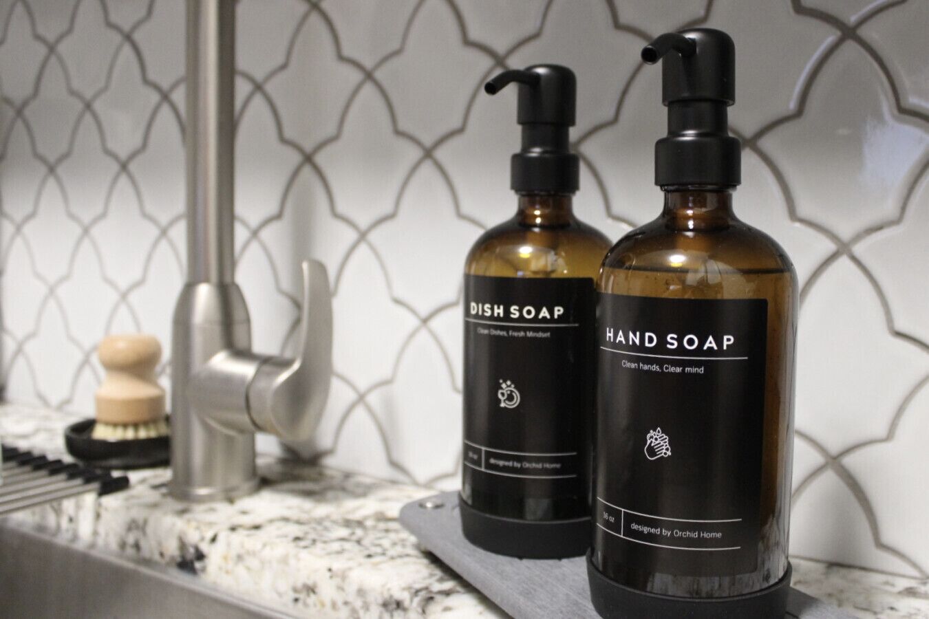 Dos botellas de detergente para platos y jabón de manos sobre una encimera de cocina.