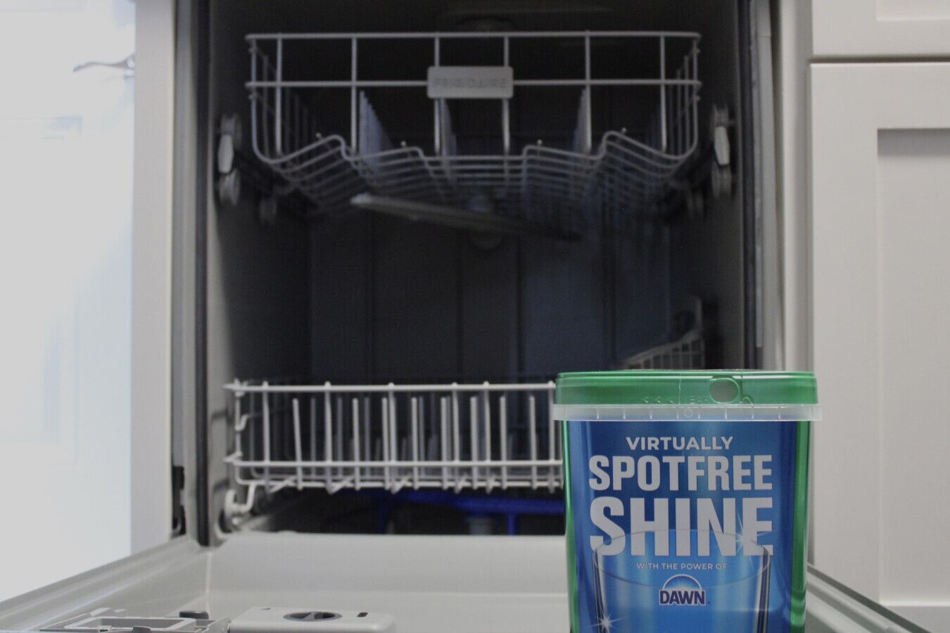 A dishwasher with a container of Dawn dish soap in front of it.