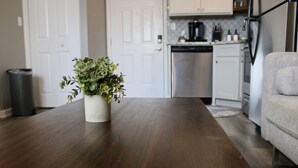 Una cocina con una mesa de madera, una planta en maceta y un sofá gris.