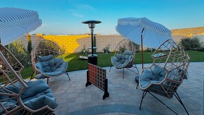 A patio with four wicker chairs, a table, and two umbrellas. - •Charming One-Level Home • Feels Like Home (Menifee)