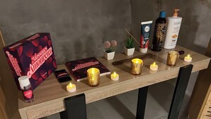Et bord med stearinlys, en bog, en flaske og en æske.