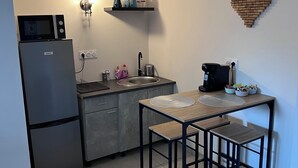 Et lille køkken med køleskab, mikroovn, vask og en spiseplads med barstole.