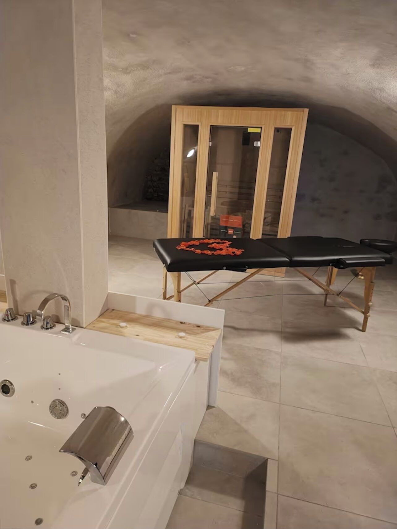 Un baño con una bañera, un banco de madera y una mampara de vidrio al fondo.