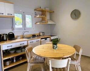Ett modernt kök med vita skåp, ett matbord i trä och en klocka på väggen.