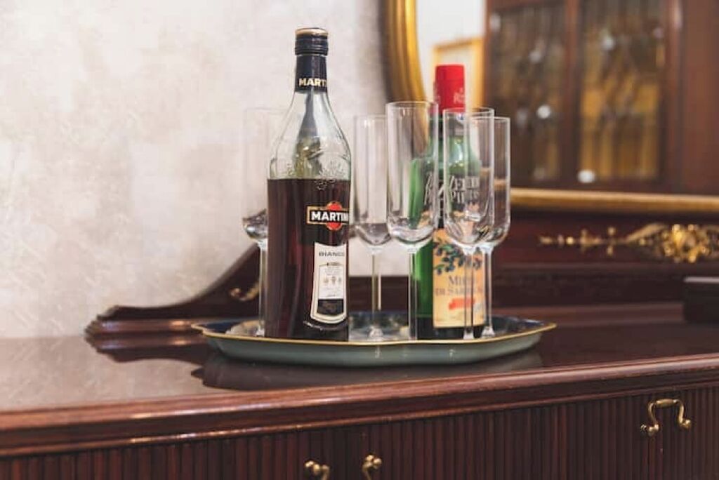 Une bouteille de Martini sur un plateau, accompagnée de deux verres et d’une autre bouteille de Martini.