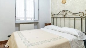 Ein Schlafzimmer mit Bett, Fenster, Heizkörper und Wanddekoration.