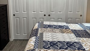 Een slaapkamer met een bed, een kaptafel en een kast met twee deuren.