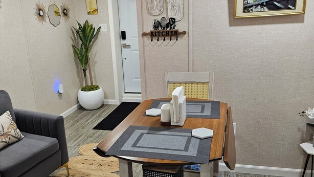 Een eetgedeelte met een houten tafel, stoelen en een decoratieve wand met een stadsgezicht.