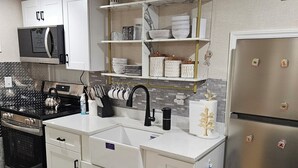 Een moderne keuken met witte kastjes, een roestvrijstalen koelkast, een magnetron en een spoelbak.