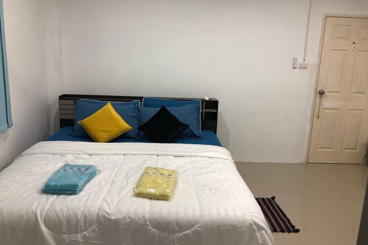 Un dormitorio con cama, mesita de noche, puerta y ventana.