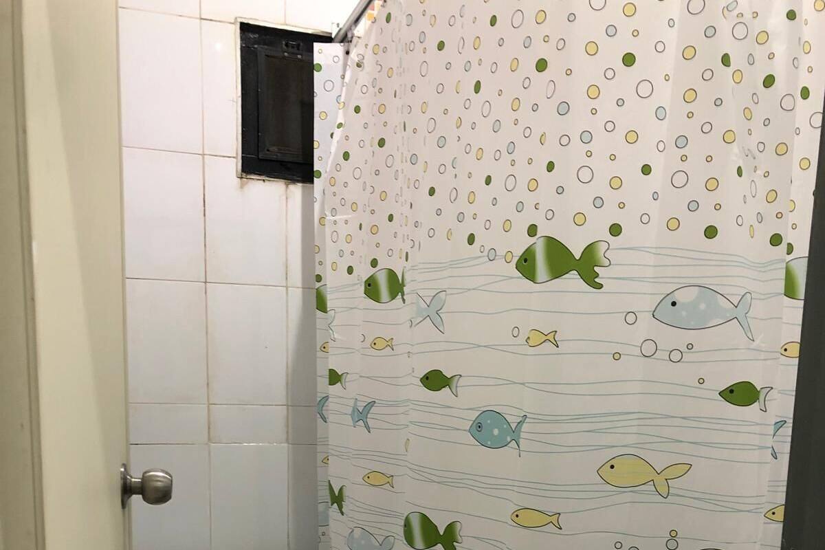 Un baño pequeño con inodoro, cortina de ducha con motivos de peces y paredes de azulejos.