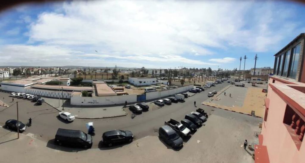 A parking lot with multiple cars and a few people.