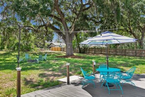 A backyard with a wooden deck, outdoor furniture, and a large umbrella. - ParkView Palms, Mid-Century Home, Sleeps 6, Pets (Mount Dora)