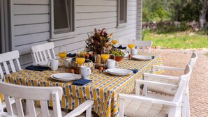 A table set for breakfast with white chairs, a patterned tablecloth, and a vase of flowers. - Casa de Palmeiros Wellness & Pool Villa (Loulé)