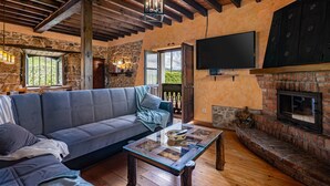 A cozy living room with a stone wall, a fireplace, a television, and a sofa.