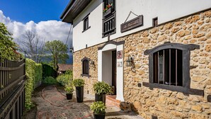 A stone building with a sign reading 'La Espinosa,' a paved courtyard with potted plants, and a wooden fence.