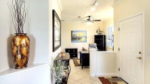 A hallway with a ceiling fan, a painting, a vase, and a door.