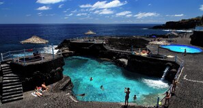 A pool area with clear blue water, surrounded by stone steps and a rocky shoreline. - El Charco Azul (San Andrés y Sauces)